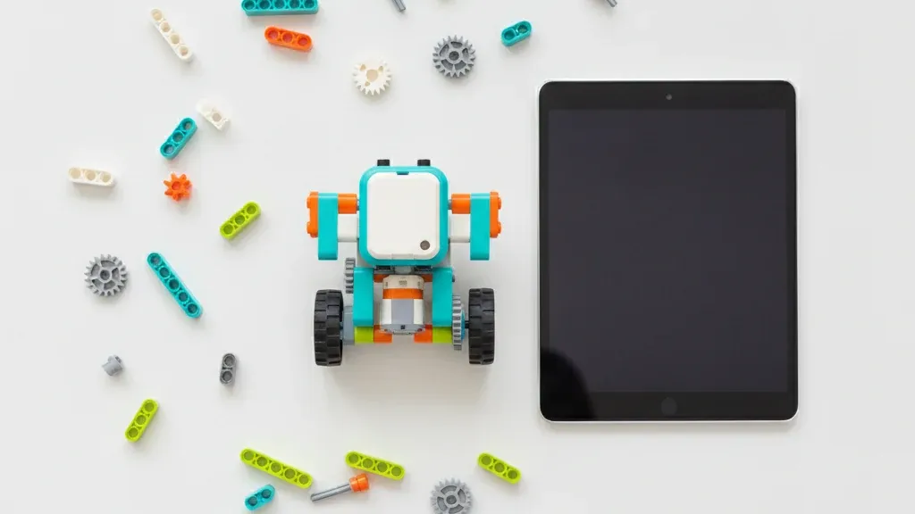 Собранная модель робота из деталей, совместимых с WeDo 2.0; рядом на столе лежат планшет и россыпь деталей