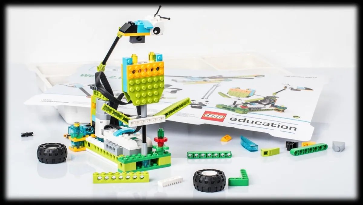 Собранная модель из конструктора РобоГуру, совместимого с WeDo 2.0, рядом с инструкцией и деталями набора